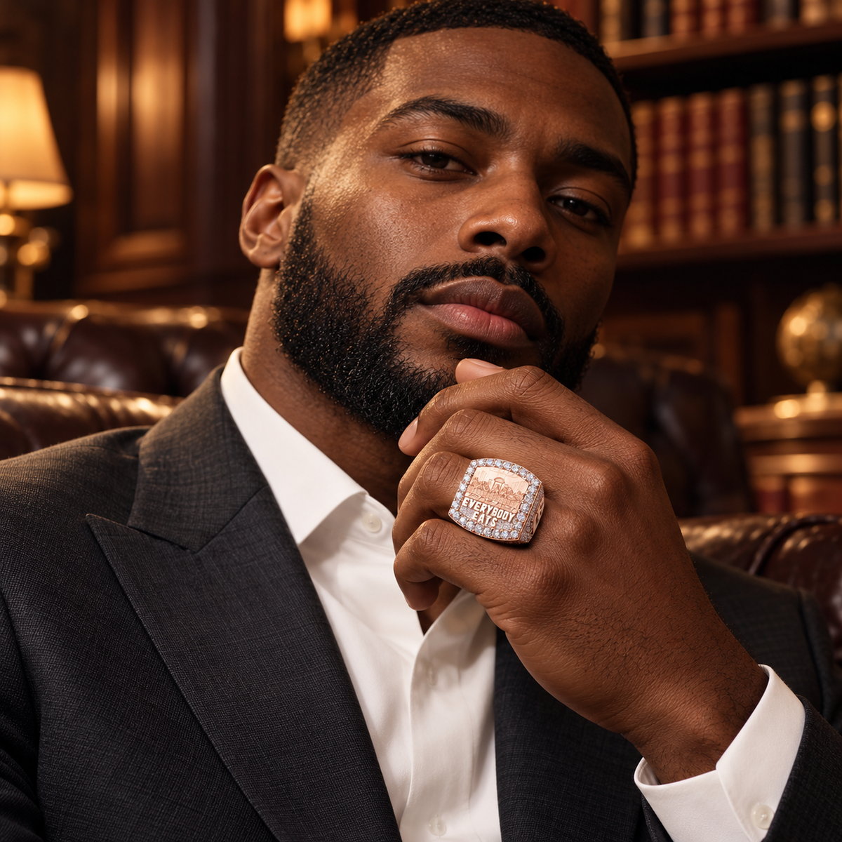 Male model wearing a custom rose gold iced statement ring in a luxury library setting
